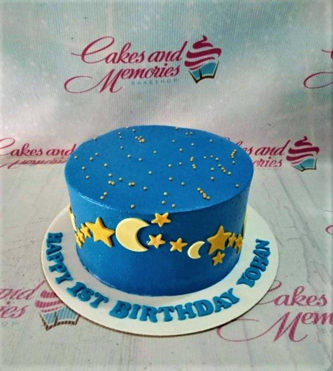 Blue night sky themed birthday cake with yellow fondant stars and crescent moons and gold sprinkles.
