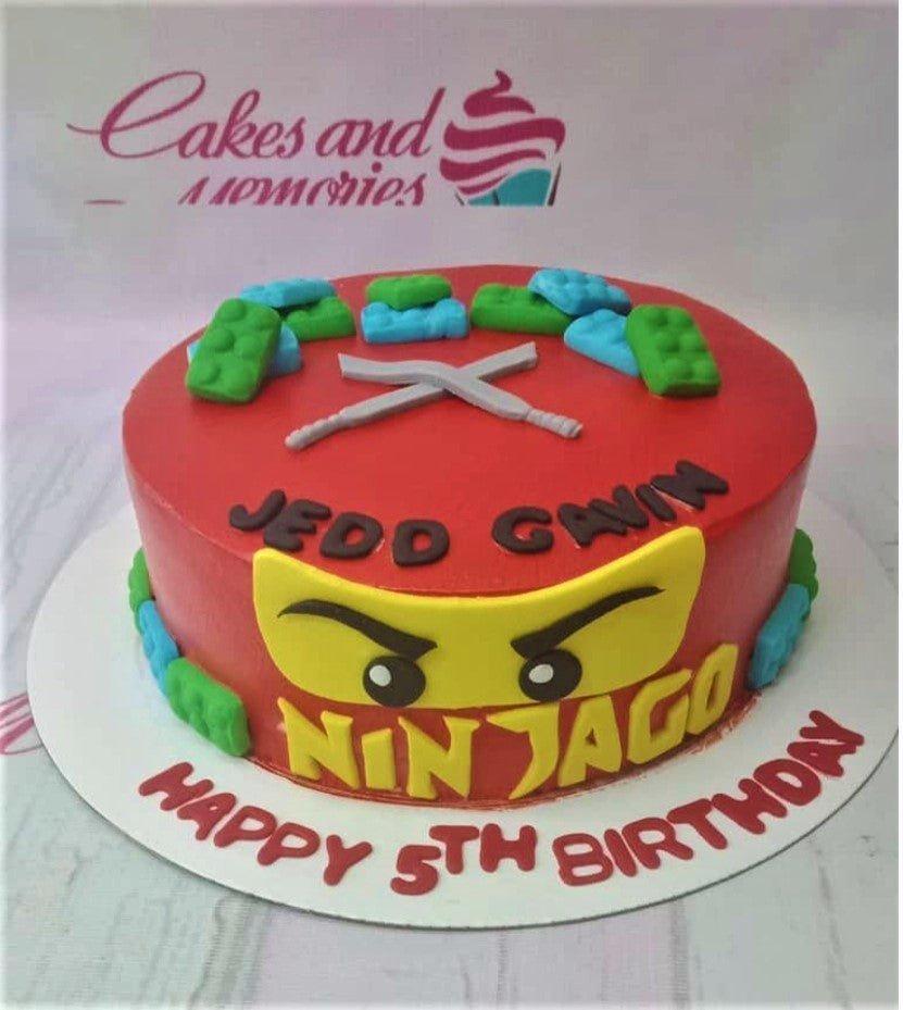 Red Ninjago themed birthday cake with Lego brick decorations and crossed swords on top.
