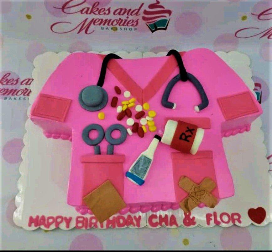 Pink nurse scrub shaped cake with fondant stethoscope, pills, medicine bottle, and thermometer decorations.