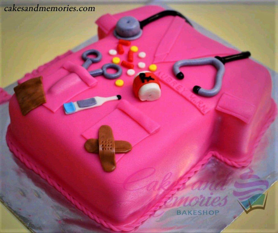 Pink nurse scrub cake with fondant medical tools including a stethoscope, thermometer, bandage, and pills.