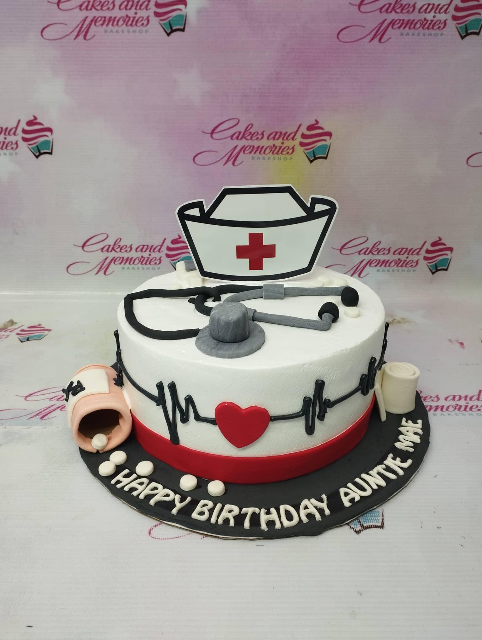 White nurse-themed birthday cake with a stethoscope, pill bottle, and EKG line decorations.