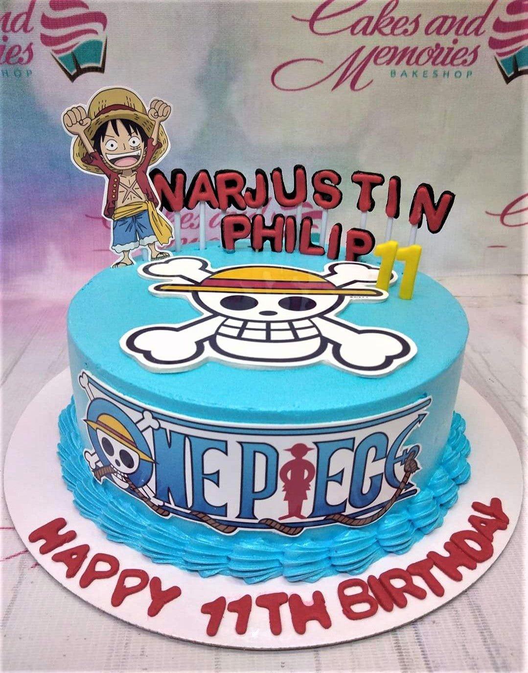 One Piece themed blue birthday cake with Luffy printout topper, Jolly Roger logo, and red gumpaste letters for Narjustin Philip.