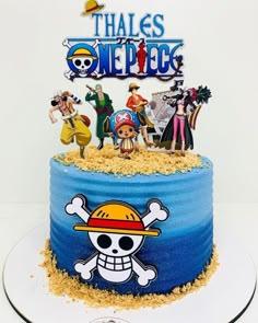 One Piece themed blue gradient cake with Luffy and crew character toppers and a large Jolly Roger logo on the side.