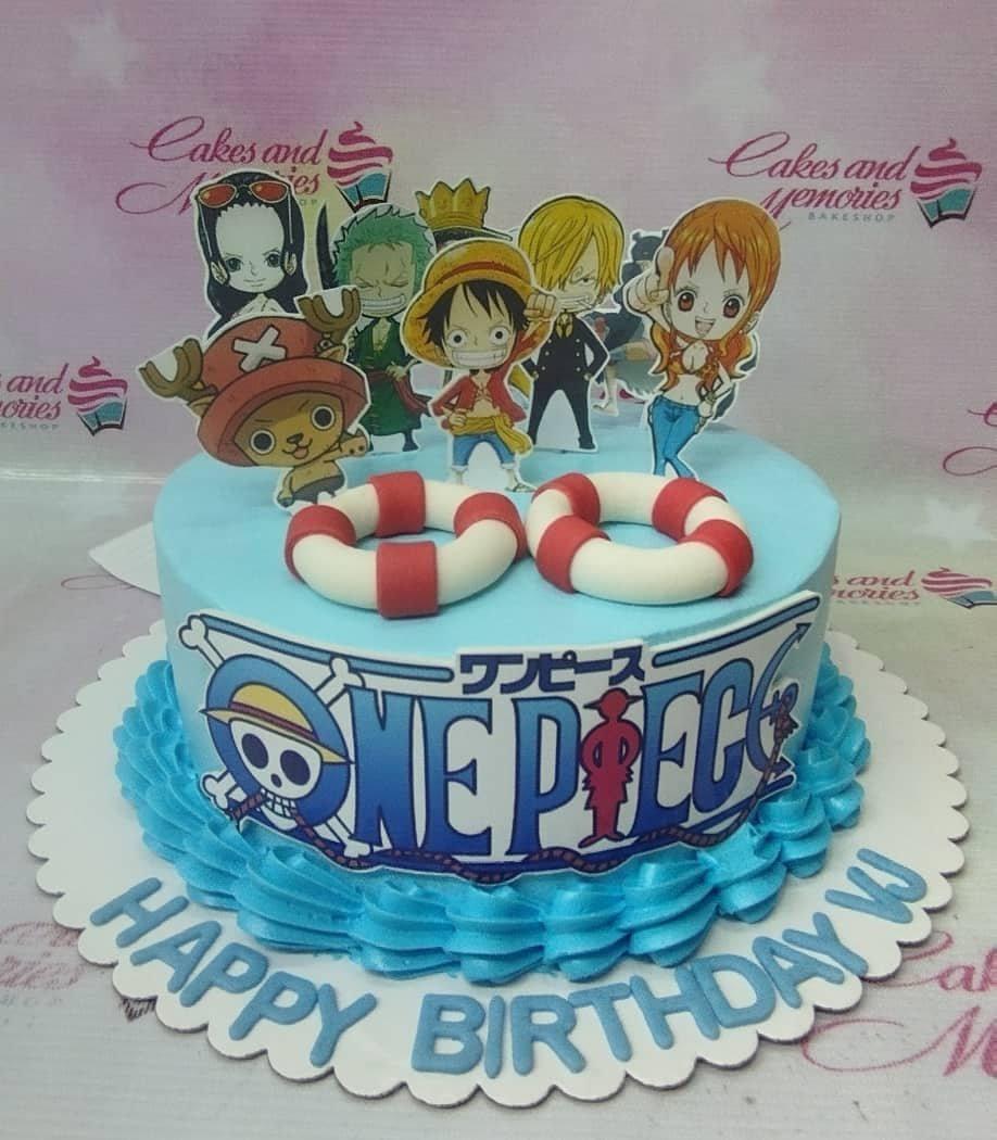 One Piece themed birthday cake with light blue icing, character printouts, and lifebuoy fondant decorations.