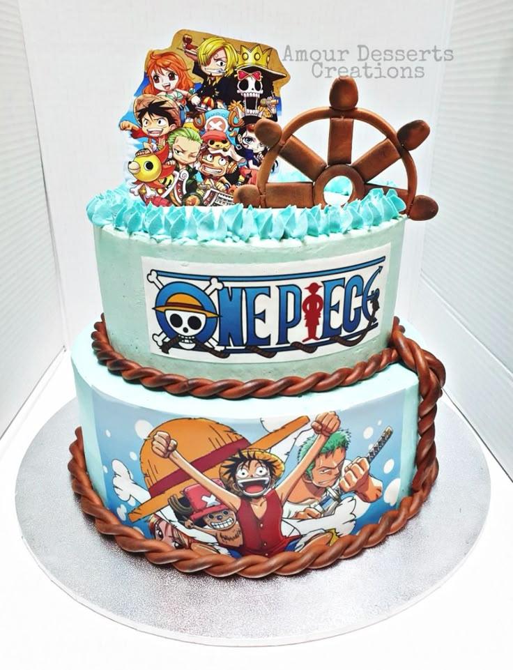 Two-tier light blue One Piece themed birthday cake with character printouts, a fondant ship wheel, and brown rope borders.