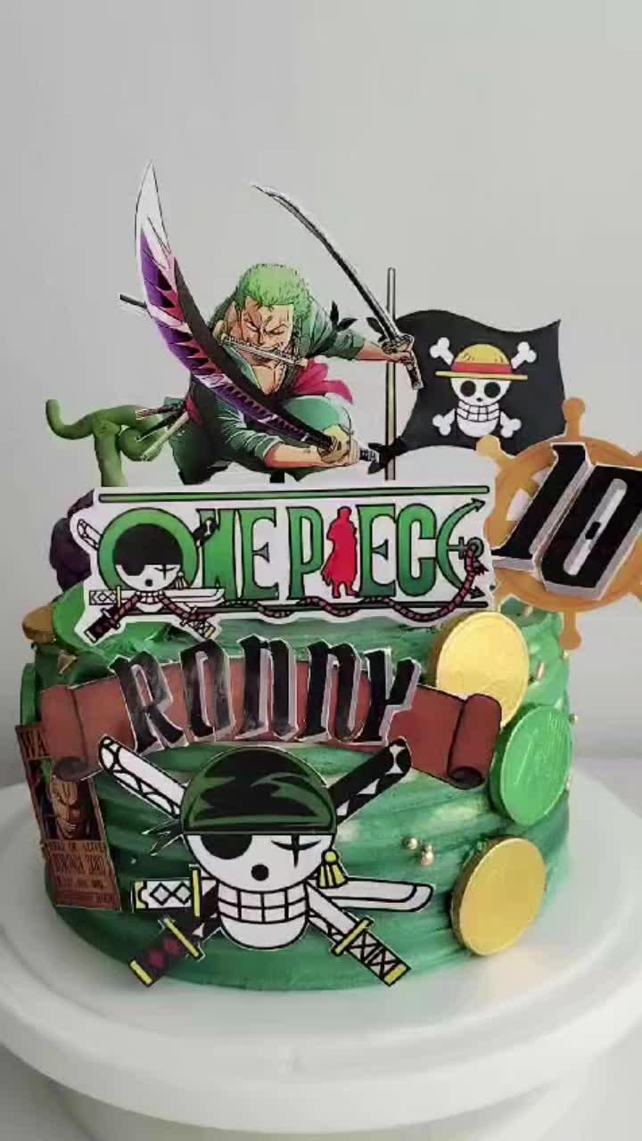 Green One Piece themed birthday cake for Ronny featuring Roronoa Zoro and pirate flag toppers with gold coin accents.