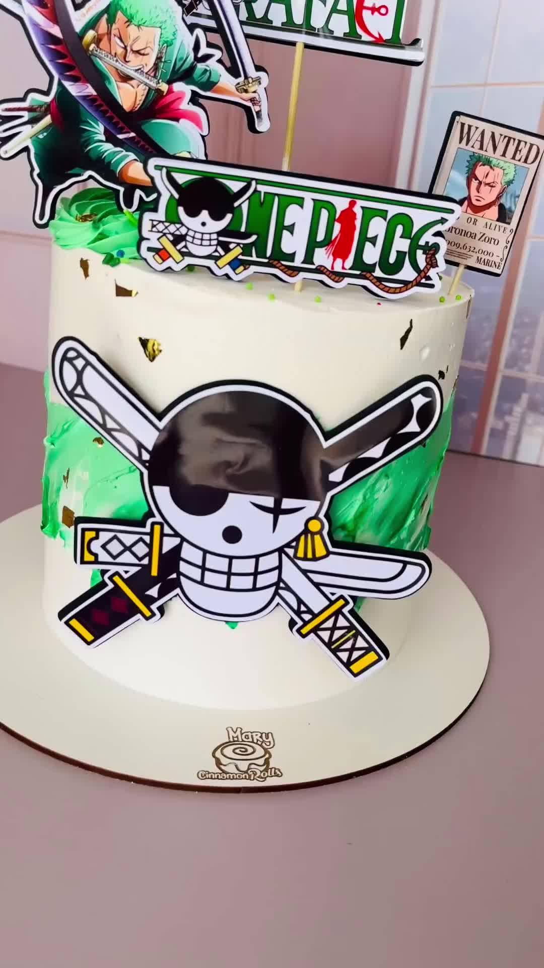 One Piece Roronoa Zoro themed birthday cake with green and white icing, character cutouts, and gold leaf accents.
