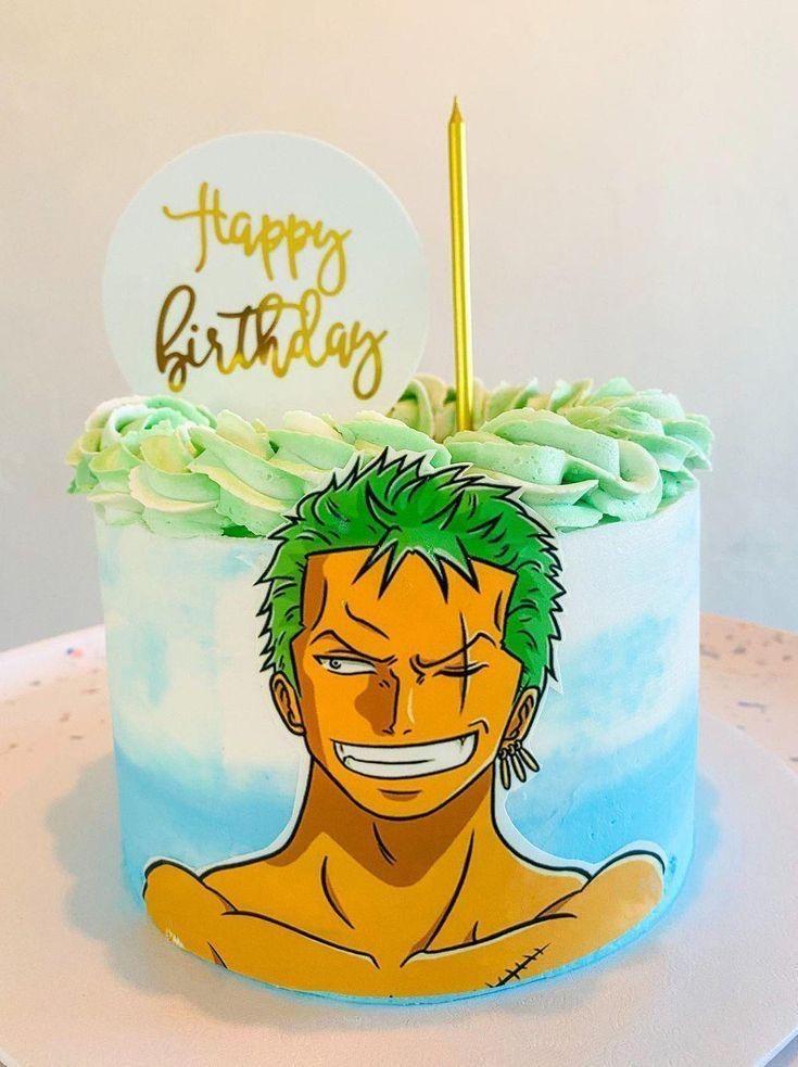 One Piece Zoro themed birthday cake with light blue watercolor icing and green rosettes featuring a Roronoa Zoro character cutout.