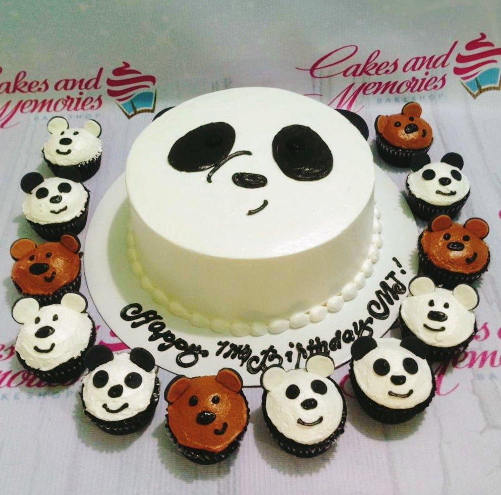 White round cake with a panda face design and matching panda and bear cupcakes arranged around the base.