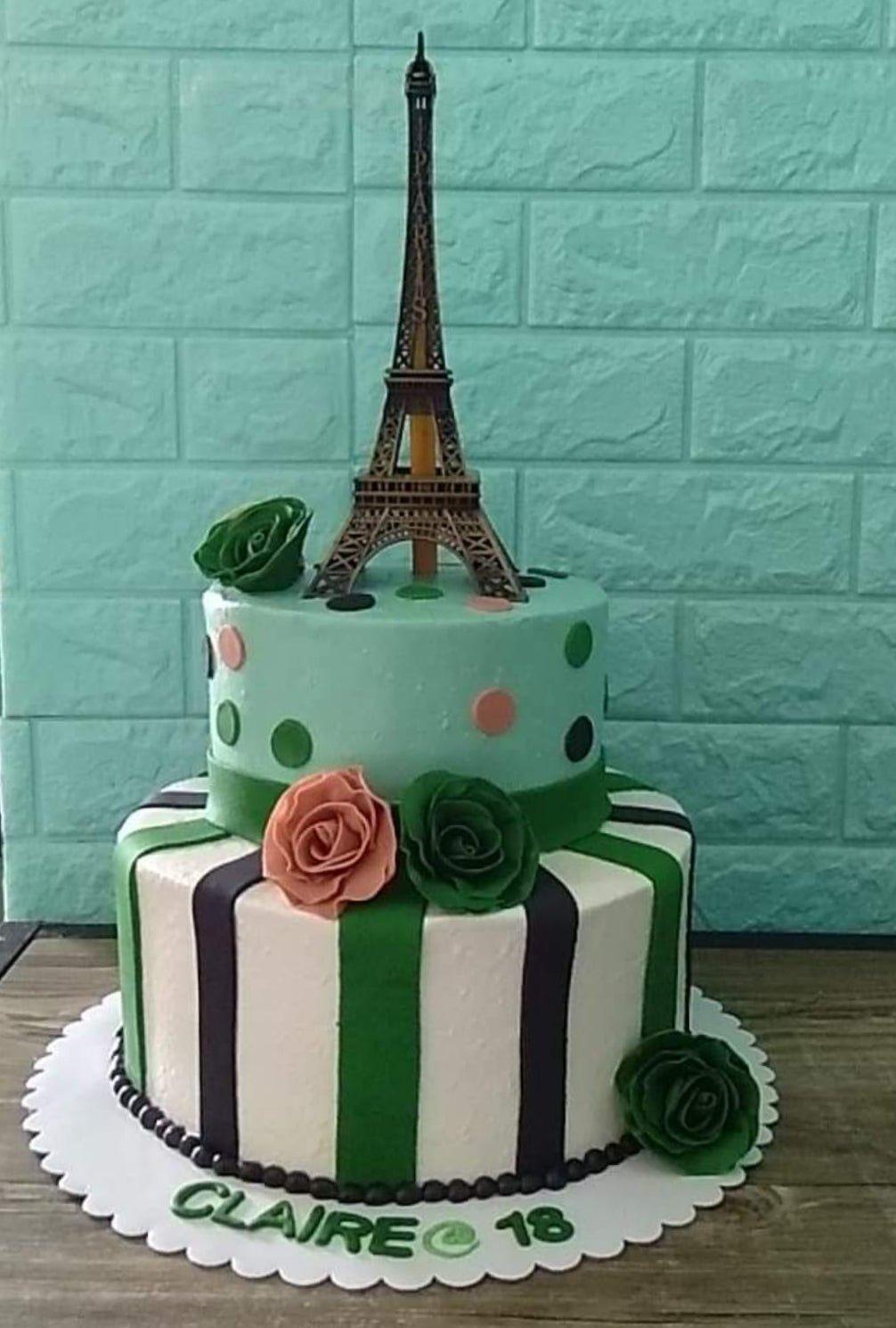Two-tier Paris themed cake with mint green and striped icing, featuring a bronze Eiffel Tower topper and fondant roses.