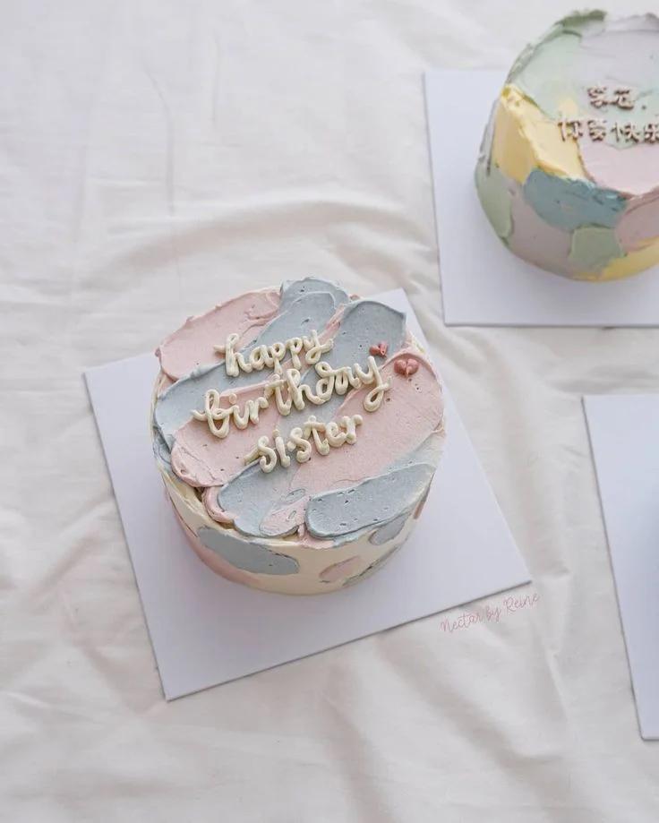 Bento cake with pastel pink and light blue palette knife icing textures and piped white message Happy Birthday Sister.