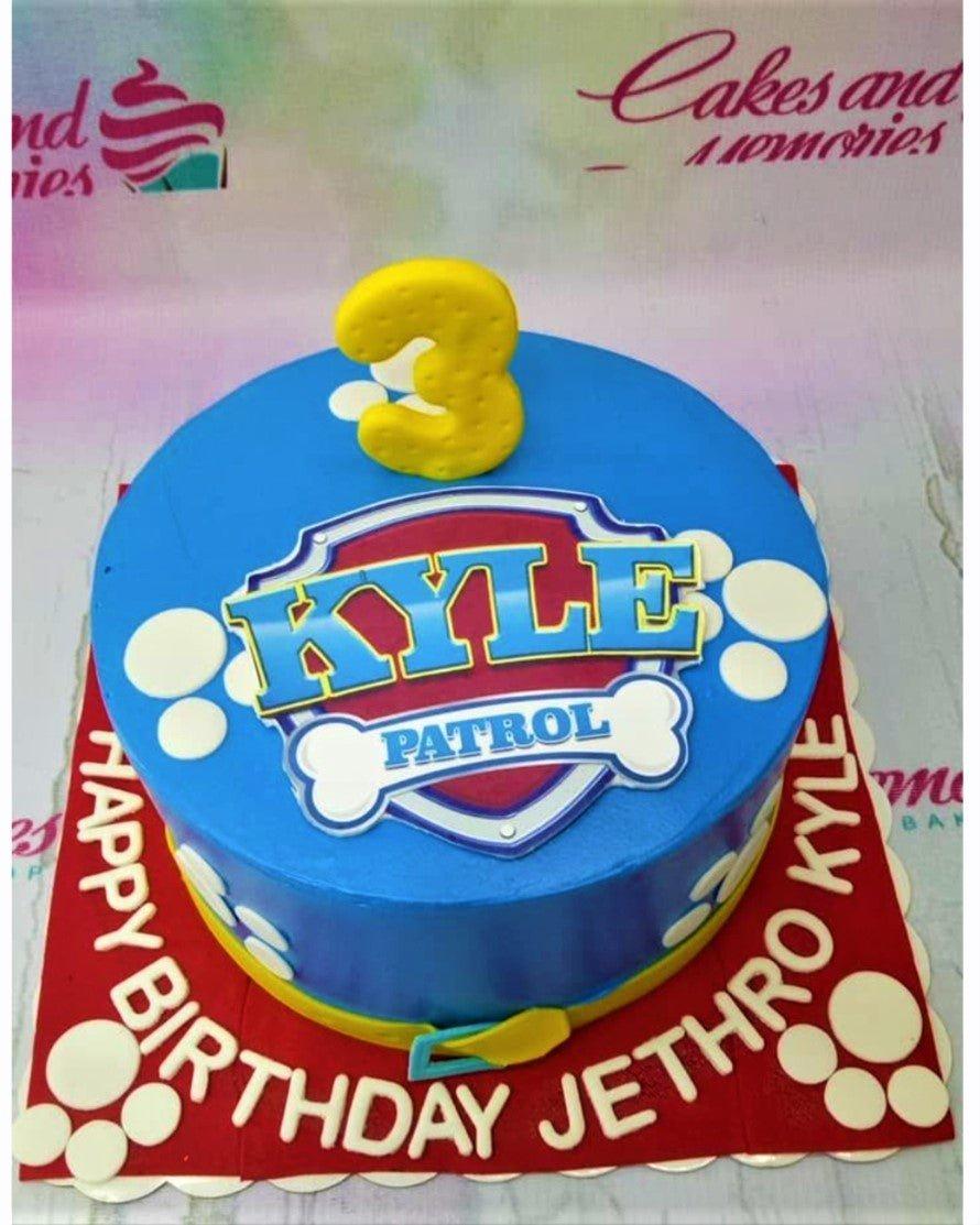 Blue Paw Patrol themed birthday cake with a large yellow number 3 topper and white paw print decorations.