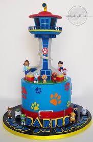 Blue Paw Patrol themed cake with a large lookout tower topper, character figurines, and paw print decorations.