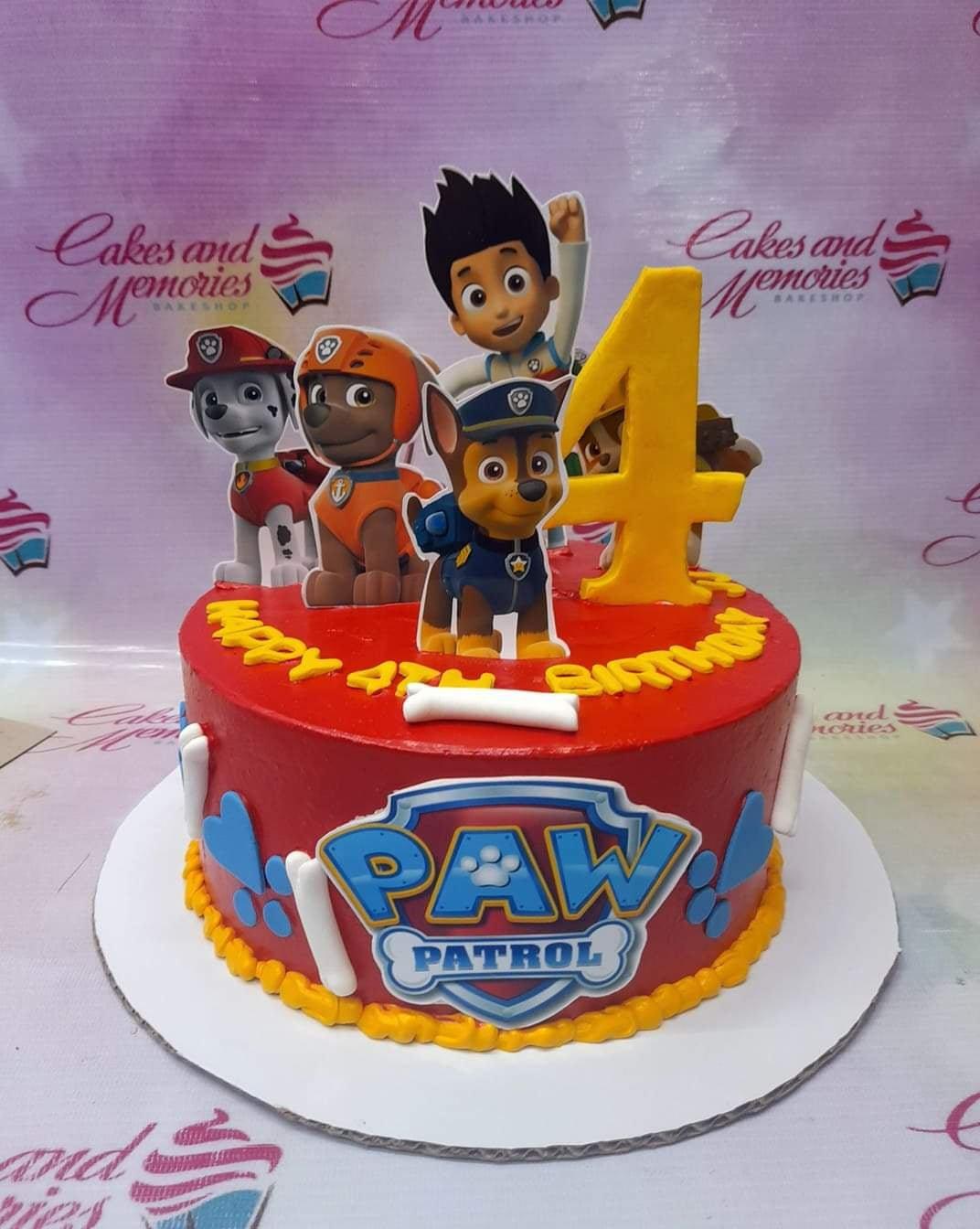 Red Paw Patrol birthday cake with printed character toppers, a large yellow number 4, and white fondant bones.