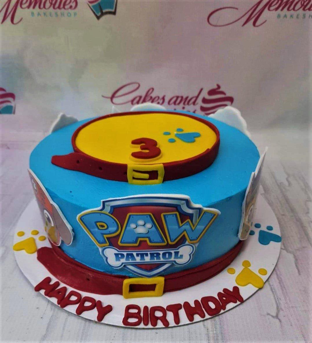 Blue Paw Patrol birthday cake with red fondant belts, character printouts, and a yellow top with a red number 3.