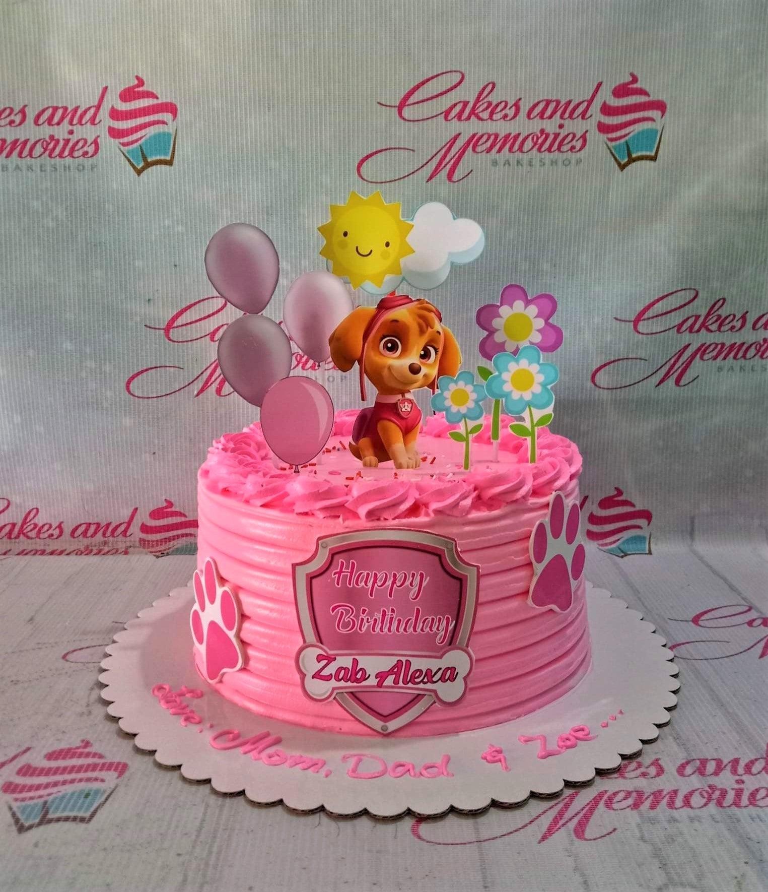 Pink Paw Patrol Skye themed birthday cake with pink icing ridges, character printouts, and paw print decorations.