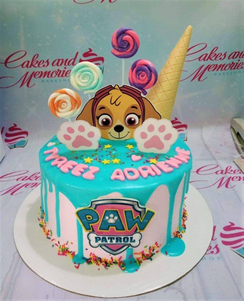 Pink and blue Paw Patrol Skye themed cake with a large Skye printout, ice cream cone, and colorful lollipops.