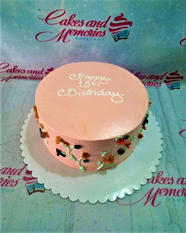 Peach minimalist birthday cake with white piped message and colorful palette knife floral icing decorations on the side.