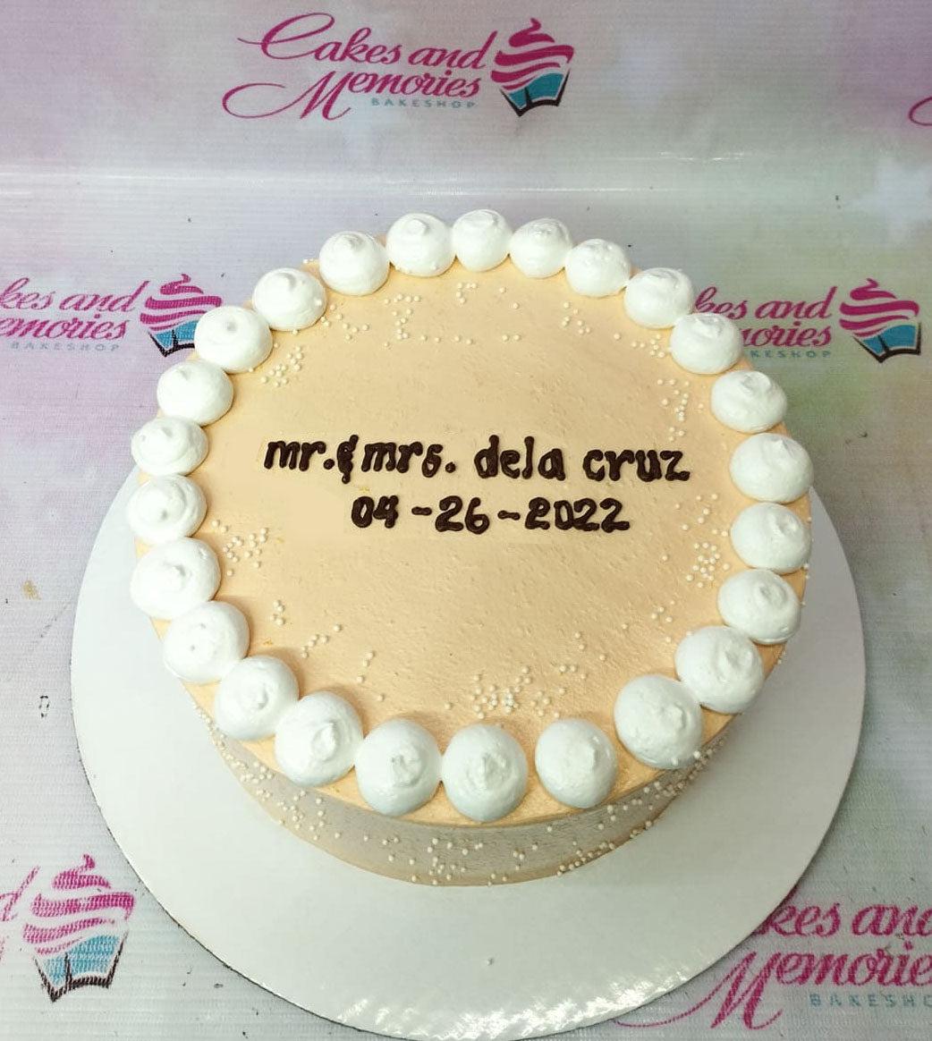 Peach minimalist cake with white icing dollops and a personalized message for Mr. and Mrs. Dela Cruz.