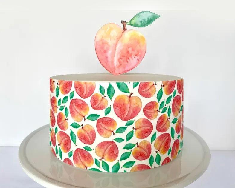 White single tier cake featuring a watercolor peach pattern on the sides and a large peach printout topper on top.
