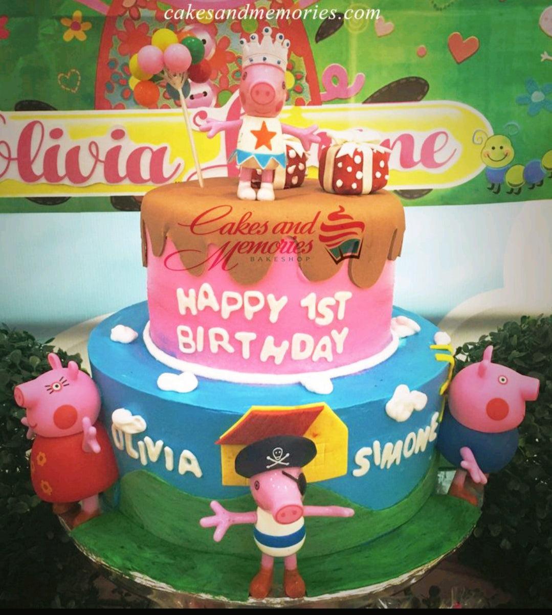 Two-tier Peppa Pig themed birthday cake with pink and blue icing, fondant figures, and a chocolate drip effect.