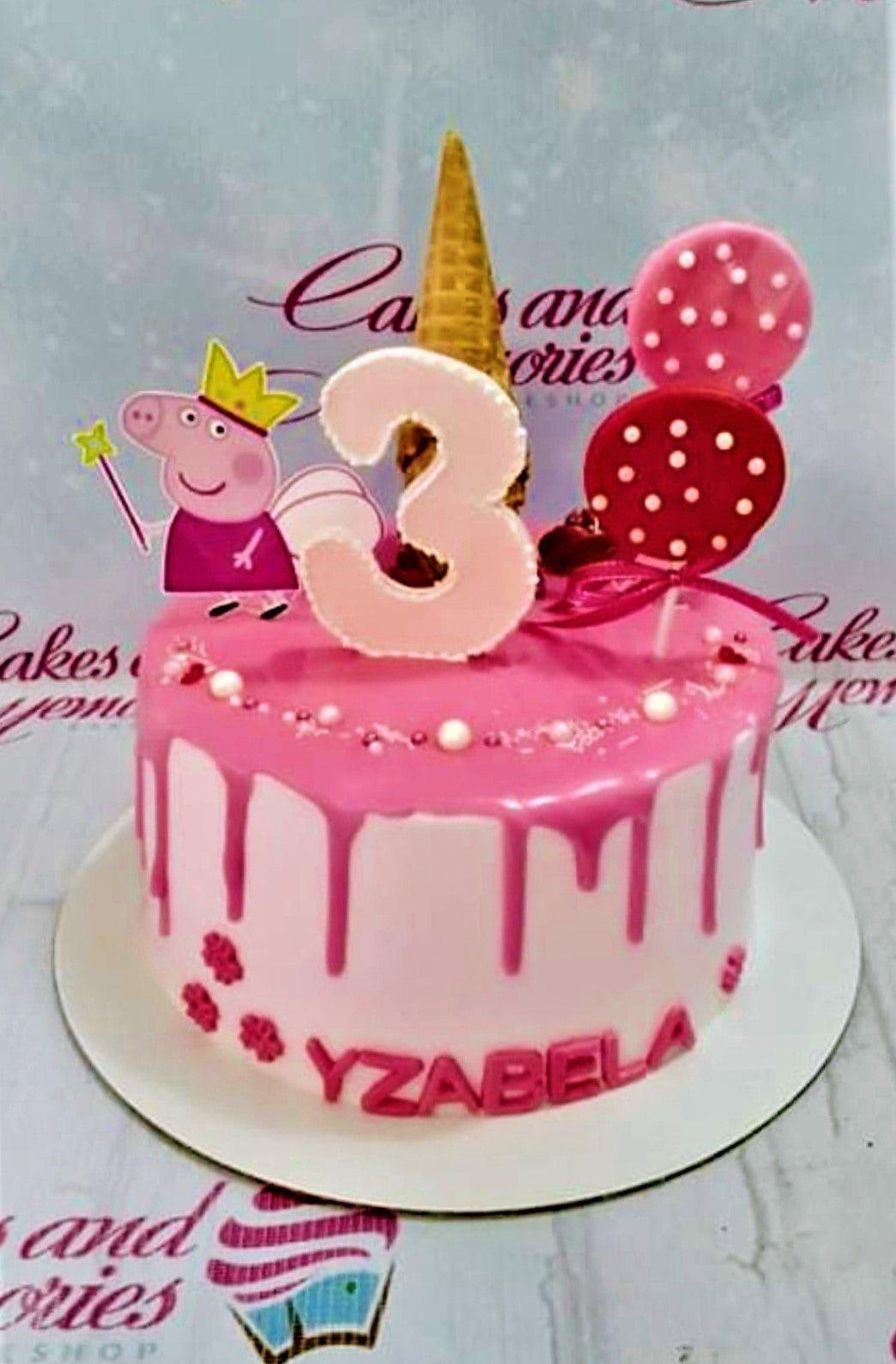 Pink Peppa Pig themed birthday cake with pink drip icing, a gold ice cream cone, and a pink number 3 topper.