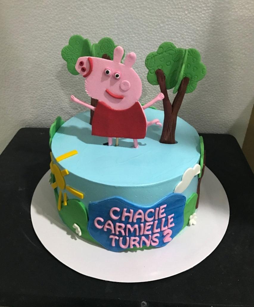 Peppa Pig themed birthday cake with light blue icing, fondant trees, and a large Peppa Pig topper for a 2nd birthday.