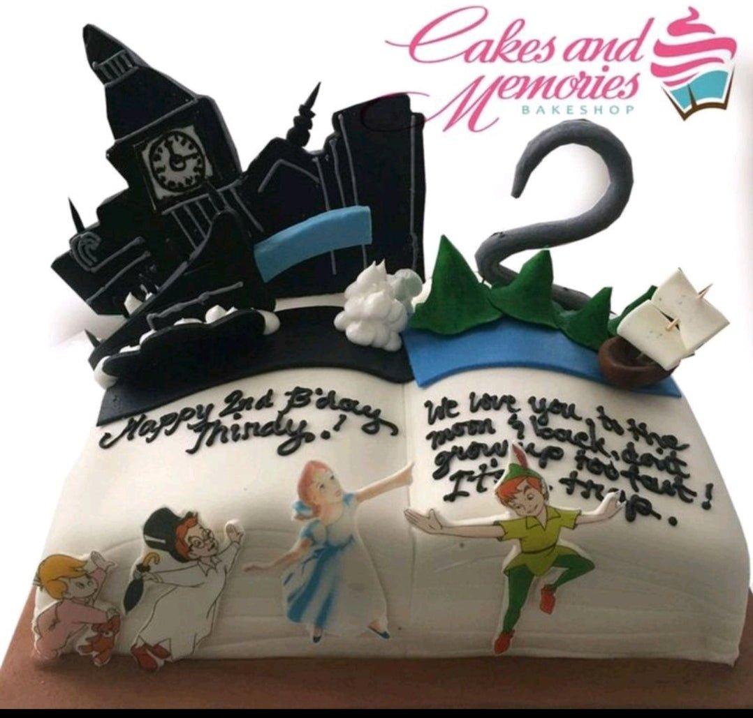 Peter Pan and Wendy themed open book cake with Big Ben silhouette, pirate ship, and hand-piped birthday messages.