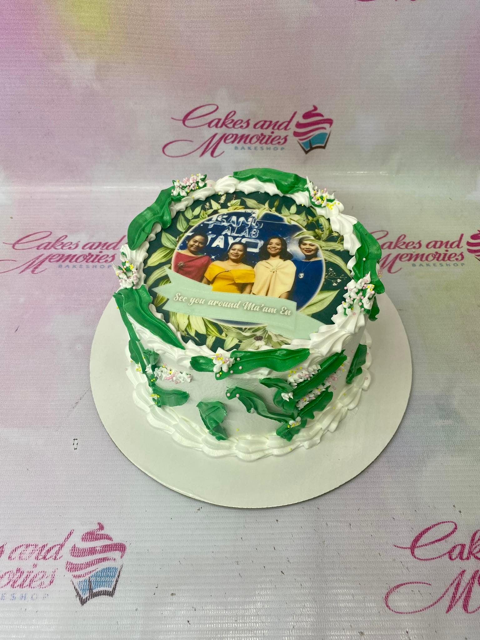 White soft-icing cake with green leaf piping, edible photo print of four women, and pink and white sprinkles.