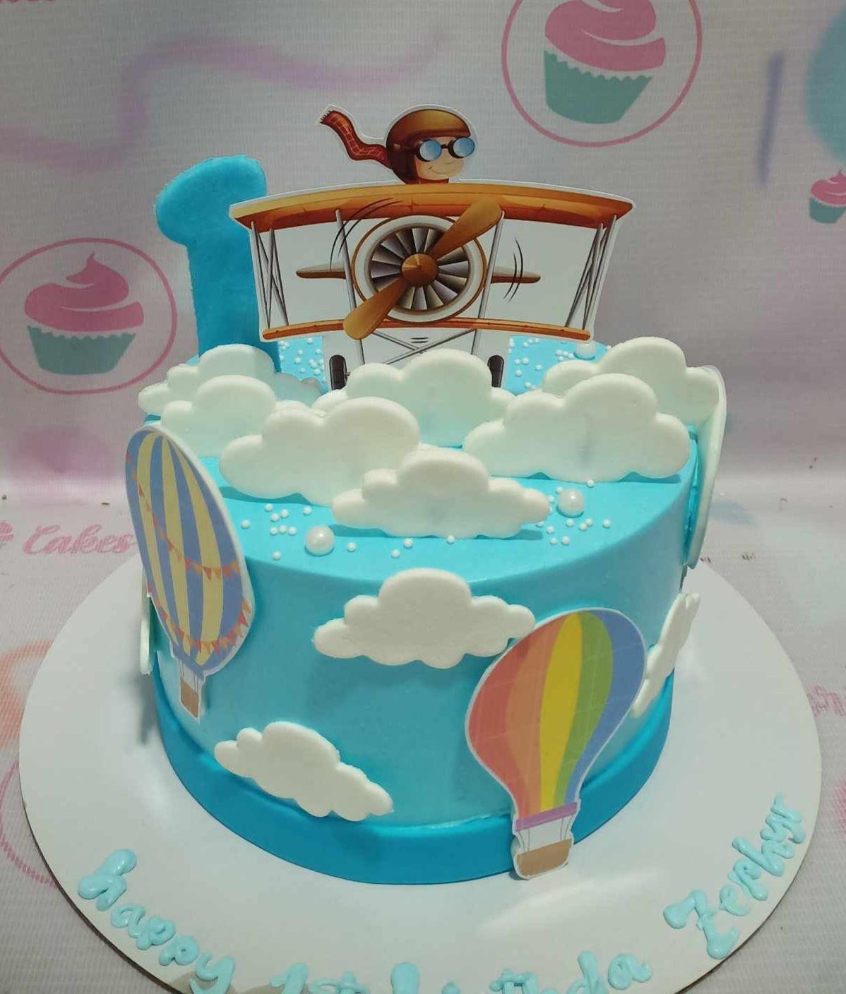 Light blue pilot themed birthday cake with a 3D number one, airplane printout, and fondant clouds.