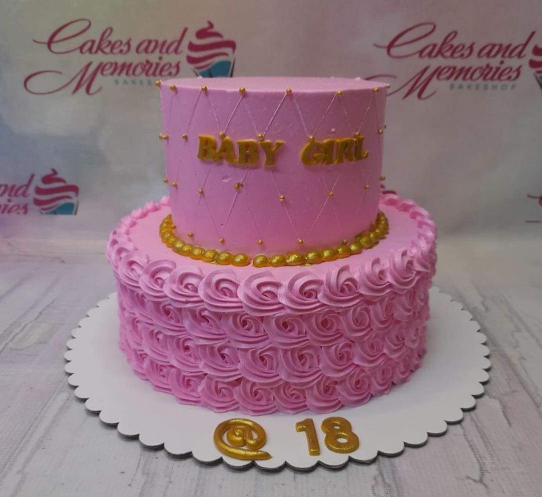 Pink two-tier birthday cake with piped icing rosettes on the bottom tier and a quilted pattern with gold pearls on the top tier.