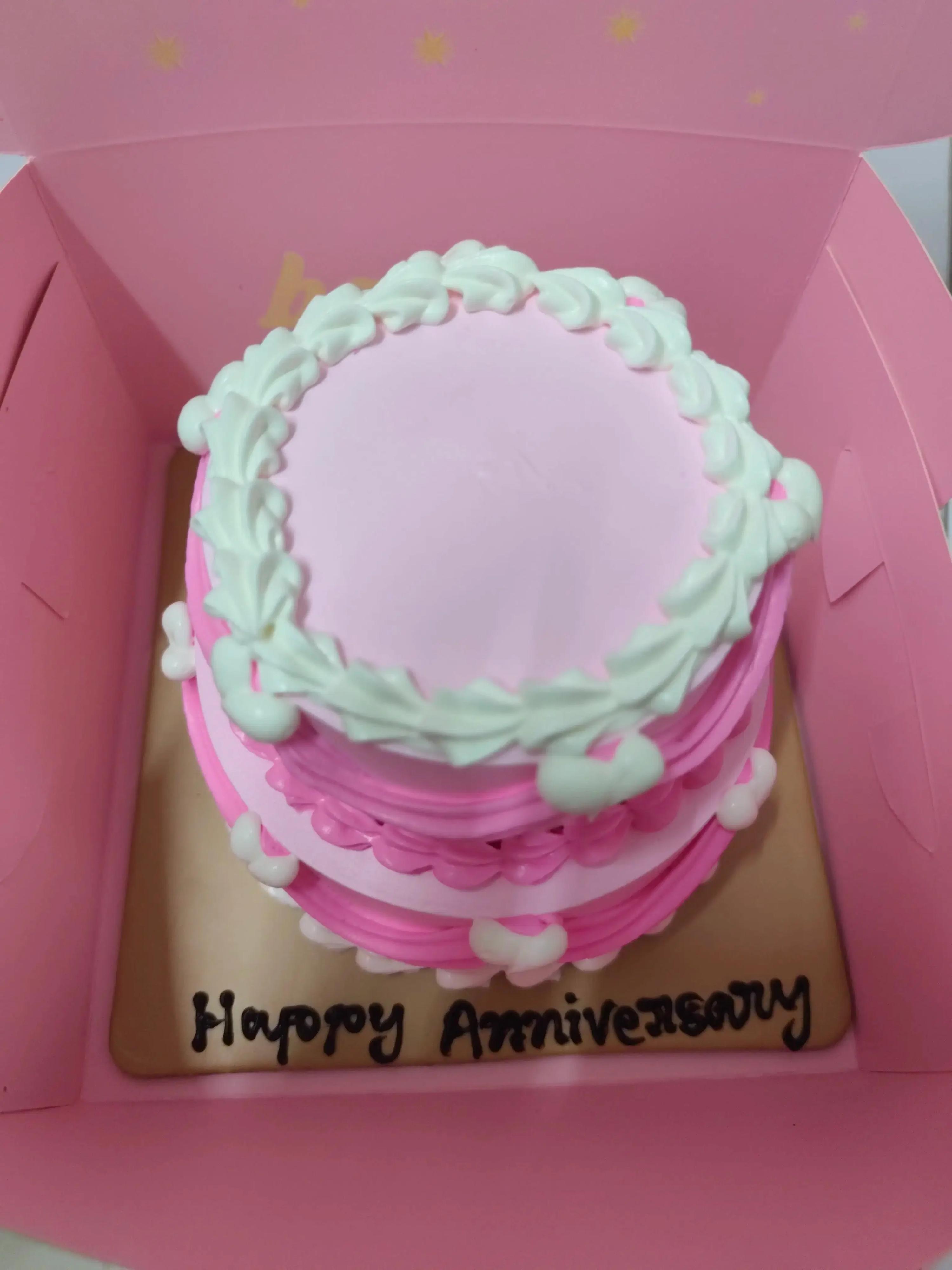Pink and white minimalist bento cake with ruffled icing borders and a Happy Anniversary message on the board.