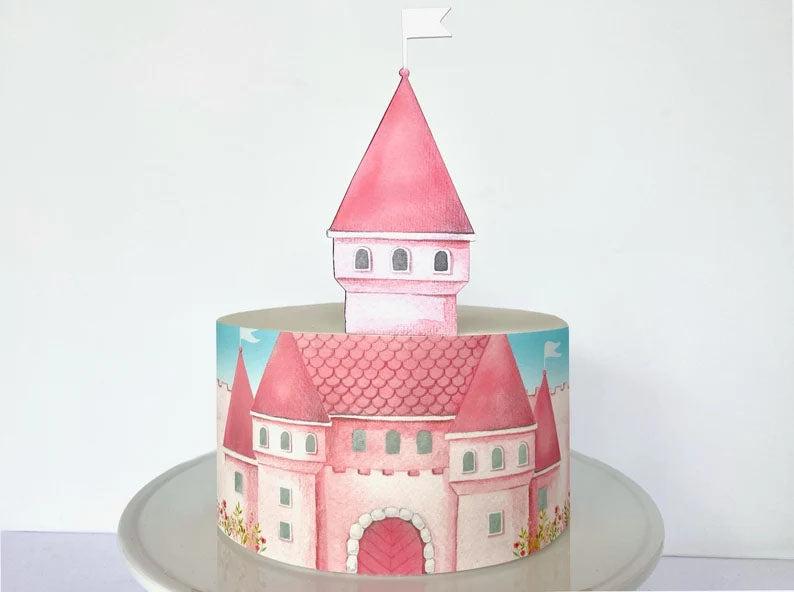 Single tier white cake with a watercolor pink castle printout wrap and a matching 3D castle tower topper with a white flag.
