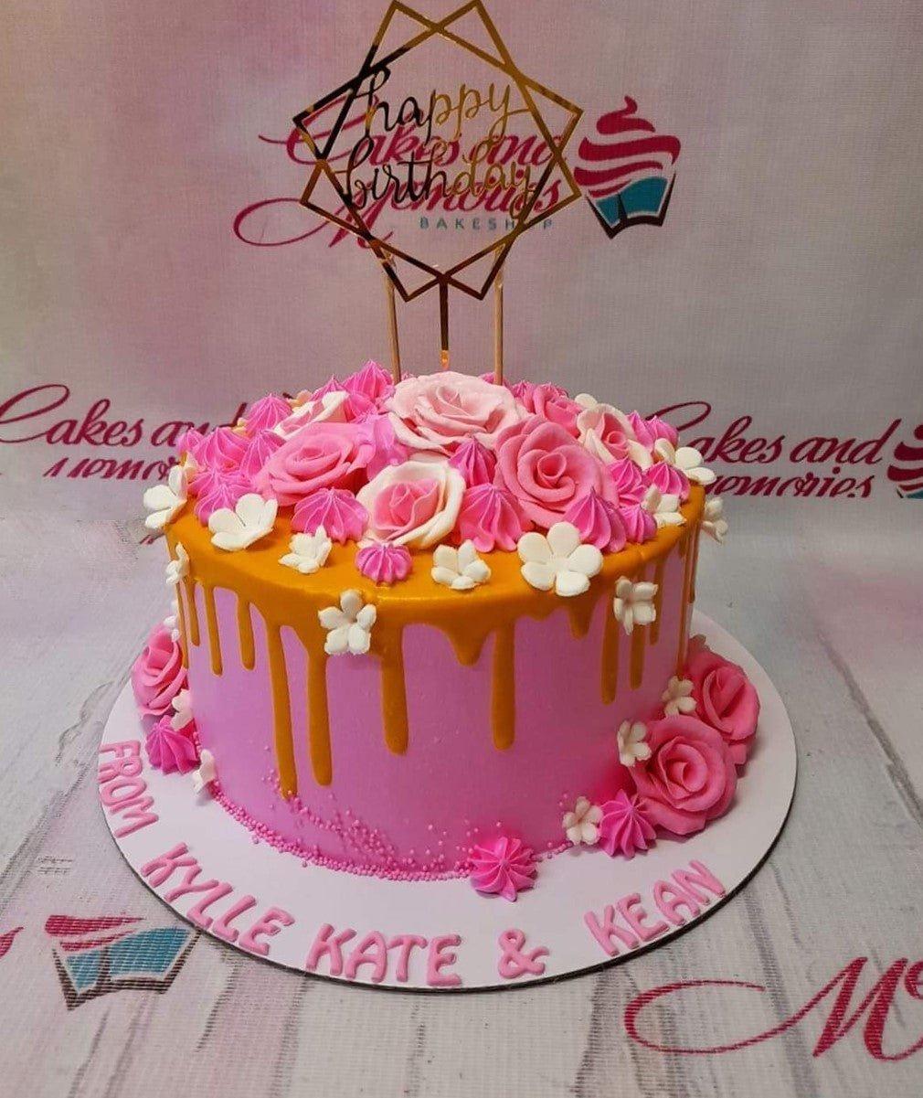 Pink 1-tier birthday cake with orange drip, pink and white icing roses, and a gold Happy Birthday topper.