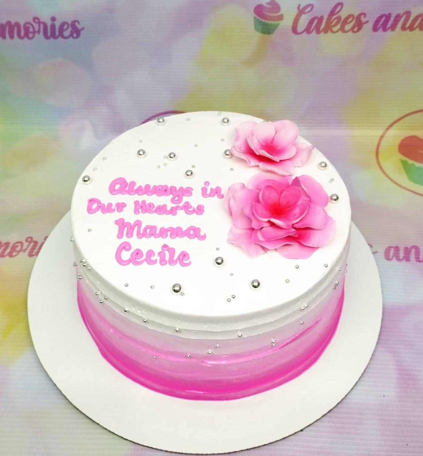 White and pink gradient cake with pink edible flowers, silver dragees, and a pink message for Mama Cecile.