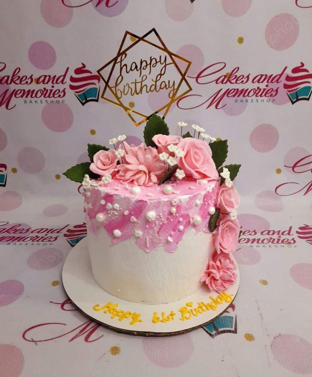 White and pink palette knife icing cake with pink gumpaste roses and a gold geometric Happy Birthday topper.