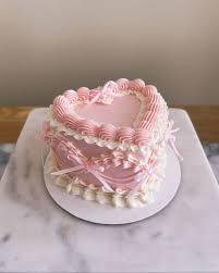 Pink heart-shaped bento cake with intricate vintage-style pink and white icing ruffles and delicate pink ribbon bows.