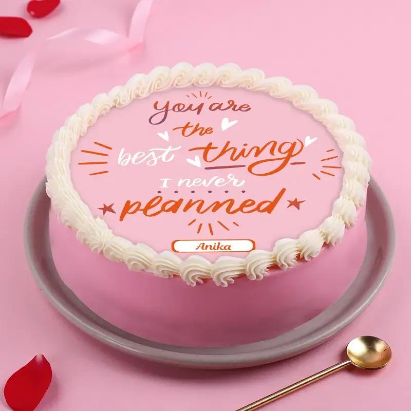 Round pink minimalist cake with white icing rosettes and a printed message 'You are the best thing I never planned' for Anika.