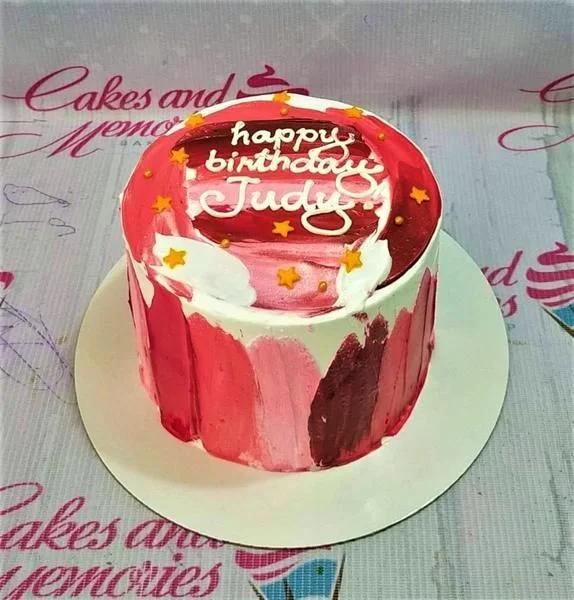 Bento cake with pink and red palette knife icing strokes, gold stars, and 'Happy Birthday Judy' message.