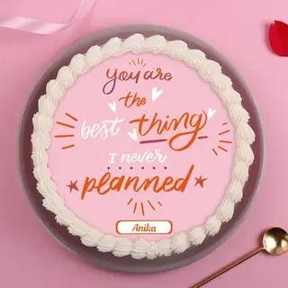 Pink bento cake with white piped icing border and a romantic message in orange and white script.