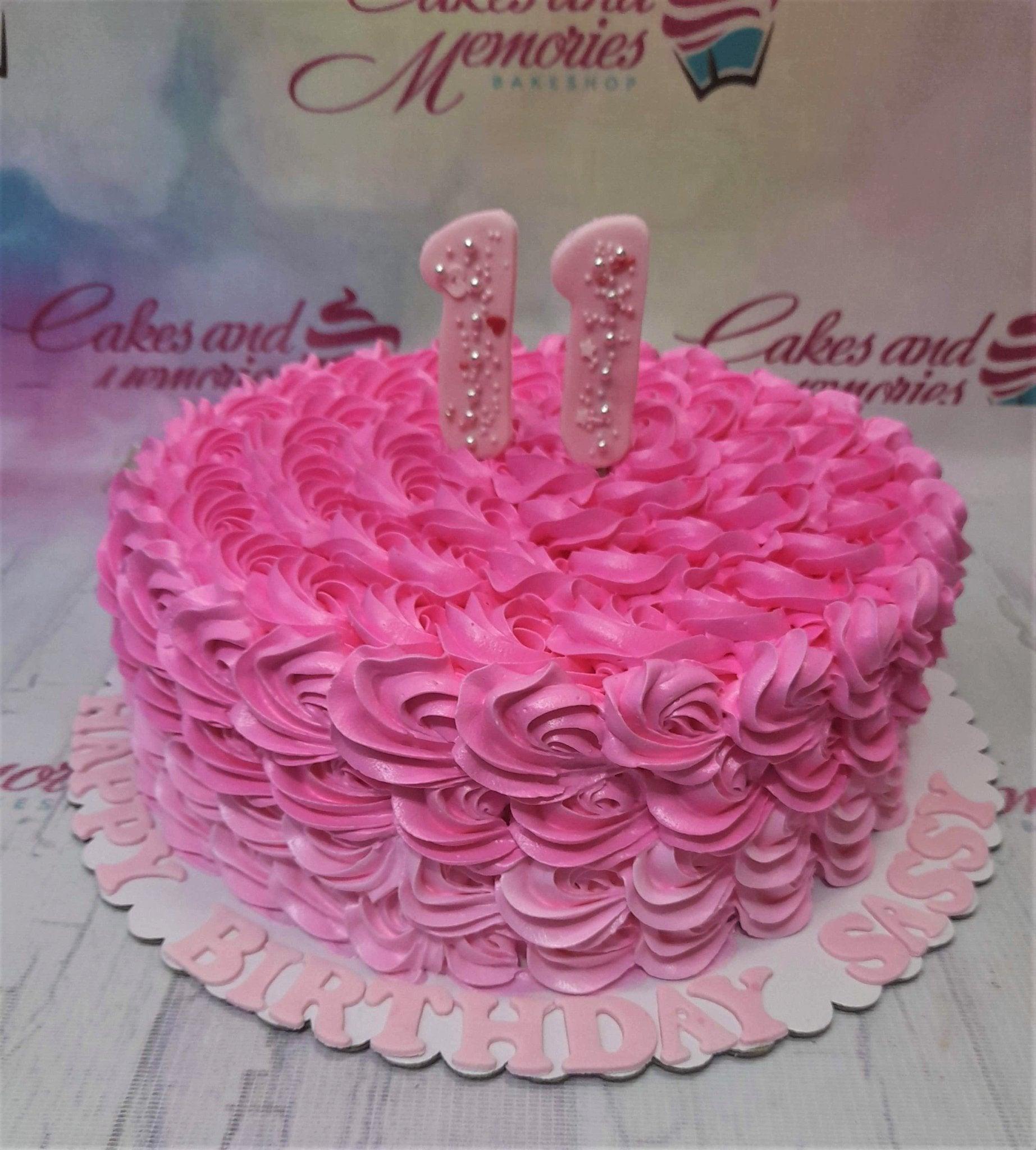 Pink rosette cake with pink number 11 toppers and Happy Birthday Sassy message on the base board.