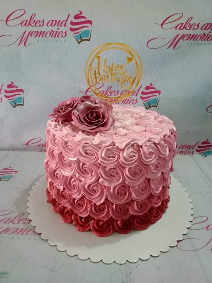 Single tier ombre pink rosette cake with two large edible roses and a gold Happy Birthday topper.