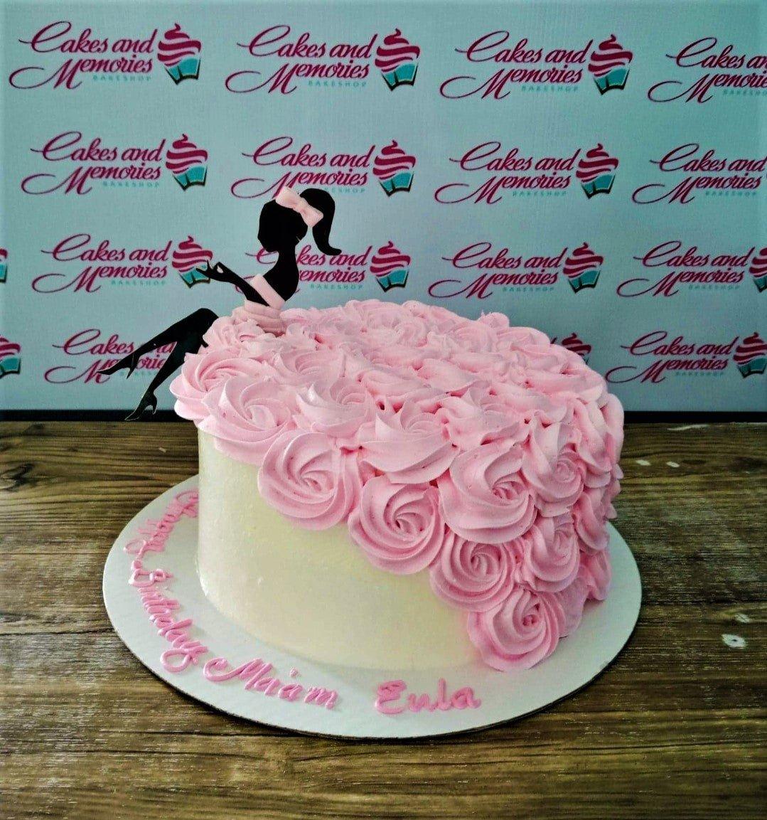 Pink rosette cake with a black silhouette lady topper and pink icing message on the board.
