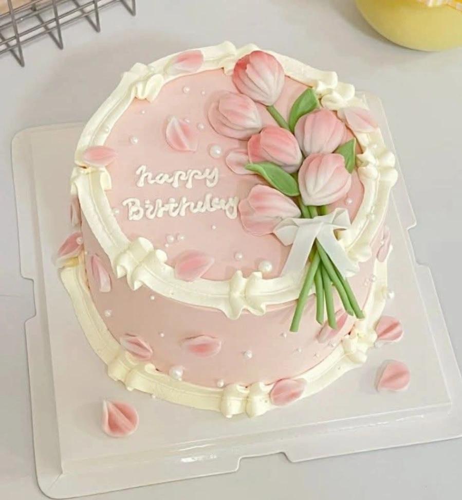 Elegant pink 1-tier birthday cake with piped cream ruffles, pink tulip bouquet topper, and white pearl sprinkles.