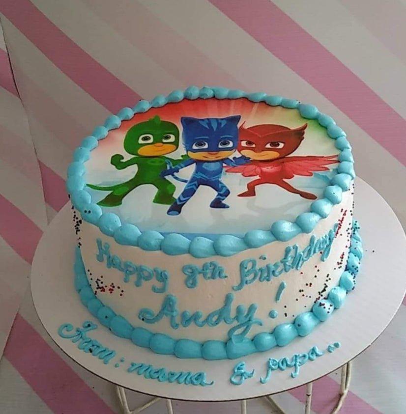PJ Masks themed birthday cake with Catboy, Owlette, and Gekko printout topper and light blue icing borders.