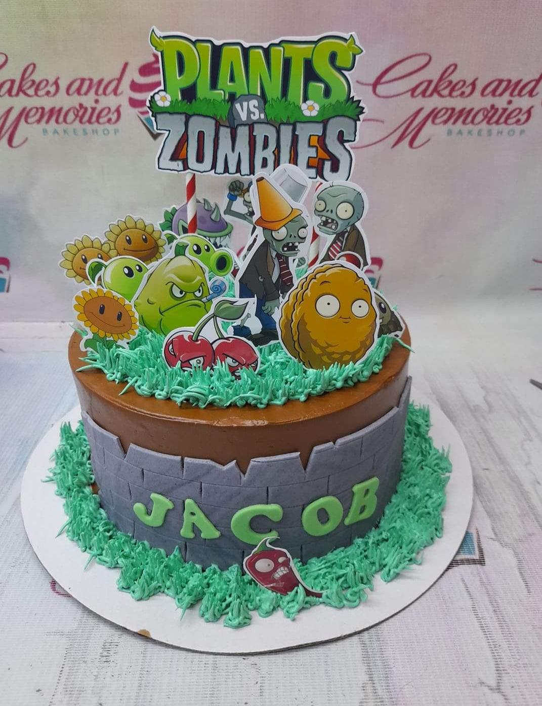Plants vs. Zombies themed chocolate cake with green icing grass, a grey brick wall fondant panel, and various character printouts.