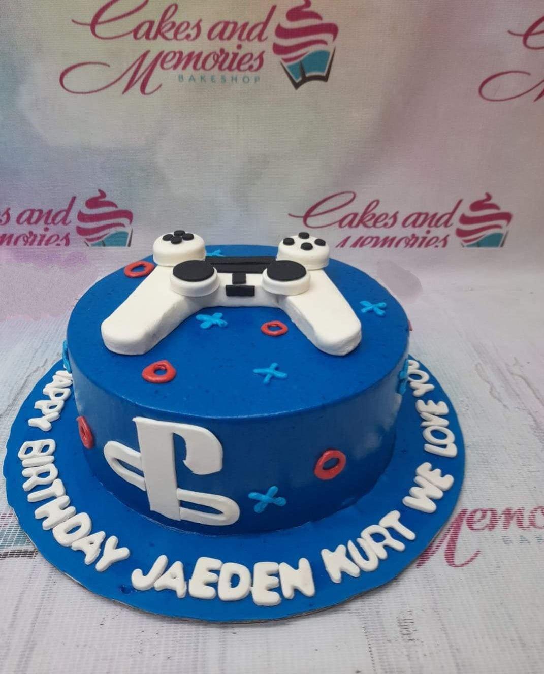 Blue PlayStation themed birthday cake with a white 3D fondant game controller and PlayStation logo on the side.