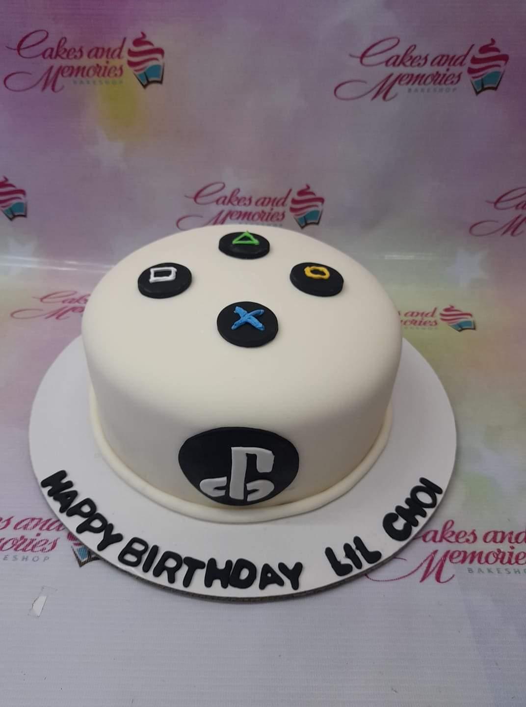 White fondant PlayStation controller themed birthday cake with black buttons and logo