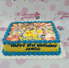 A blue and yellow rectangle cake featuring a Pokemon character scene print and blue icing decorations.