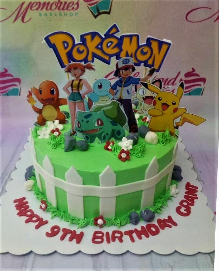 Green Pokemon themed birthday cake with Ash, Pikachu, and starter Pokemon printout toppers and a white picket fence design.